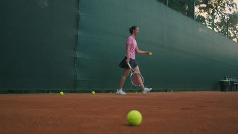 Closeup-footage-of-female-legs-in-sports-sneakers-and-prosthesis-on-her-leg-picking-up-tennis-balls-from-the-tennis-court-ground